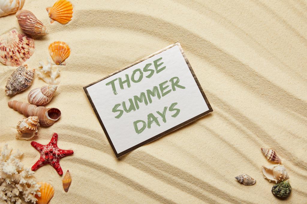 top view of card with those summer days lettering near seashells, red starfish and corals on sandy beach  - Photo, Image