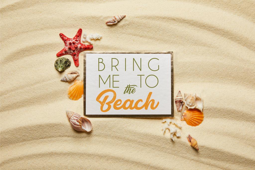 top view of placard with bring me to the beach lettering near seashells, starfish and white corals on sandy beach  - Photo, Image