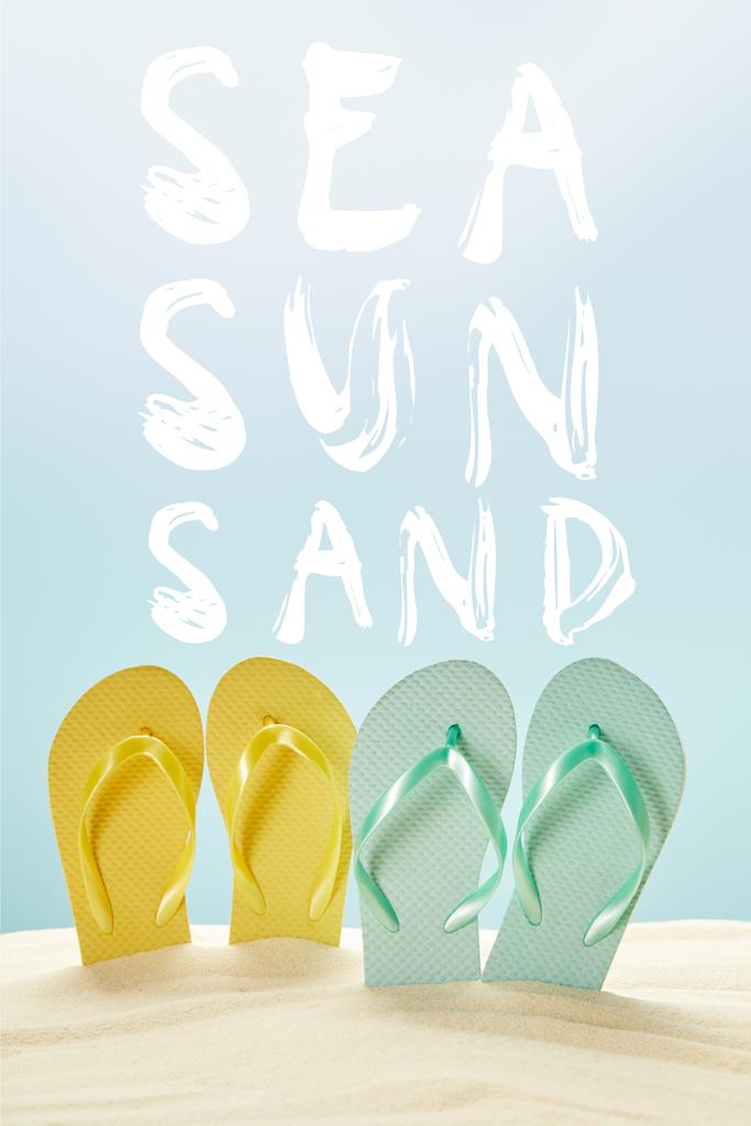 летние желтые и синие шлепанцы в золотом песке, изолированные на голубом с морской, солнечной и песчаной надписью
 - Фото, изображение