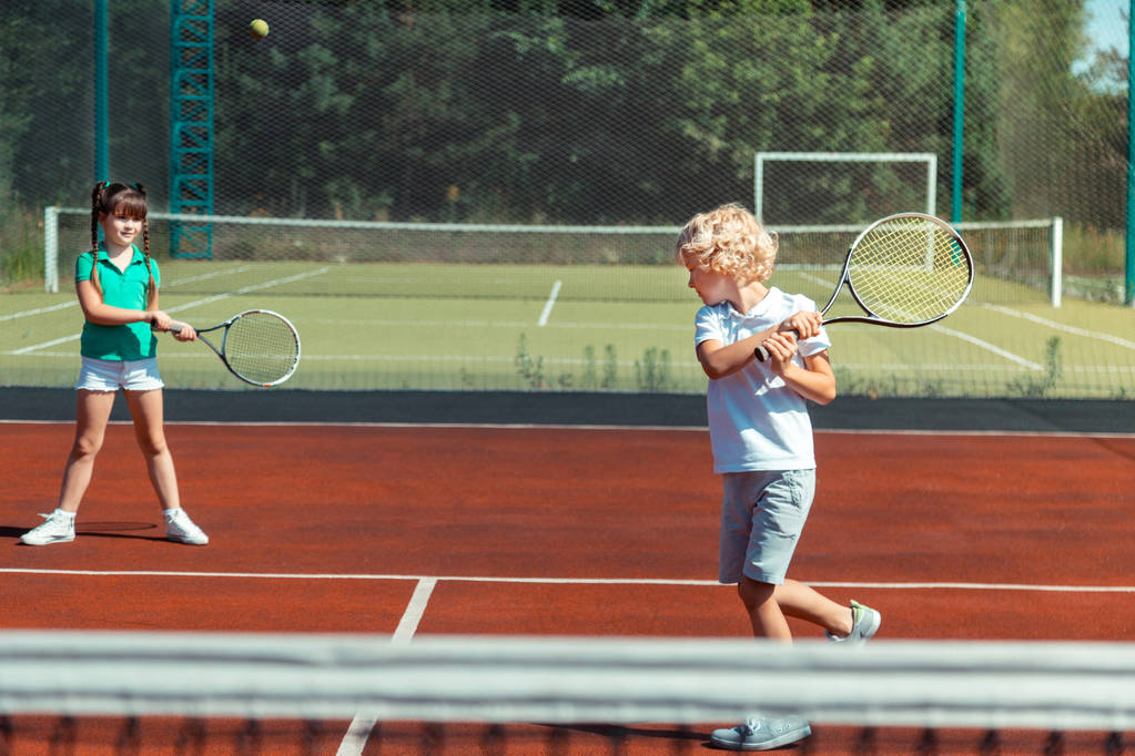 Bratr udeřil do tenisového míče a hrál si se sestrou - Fotografie, Obrázek
