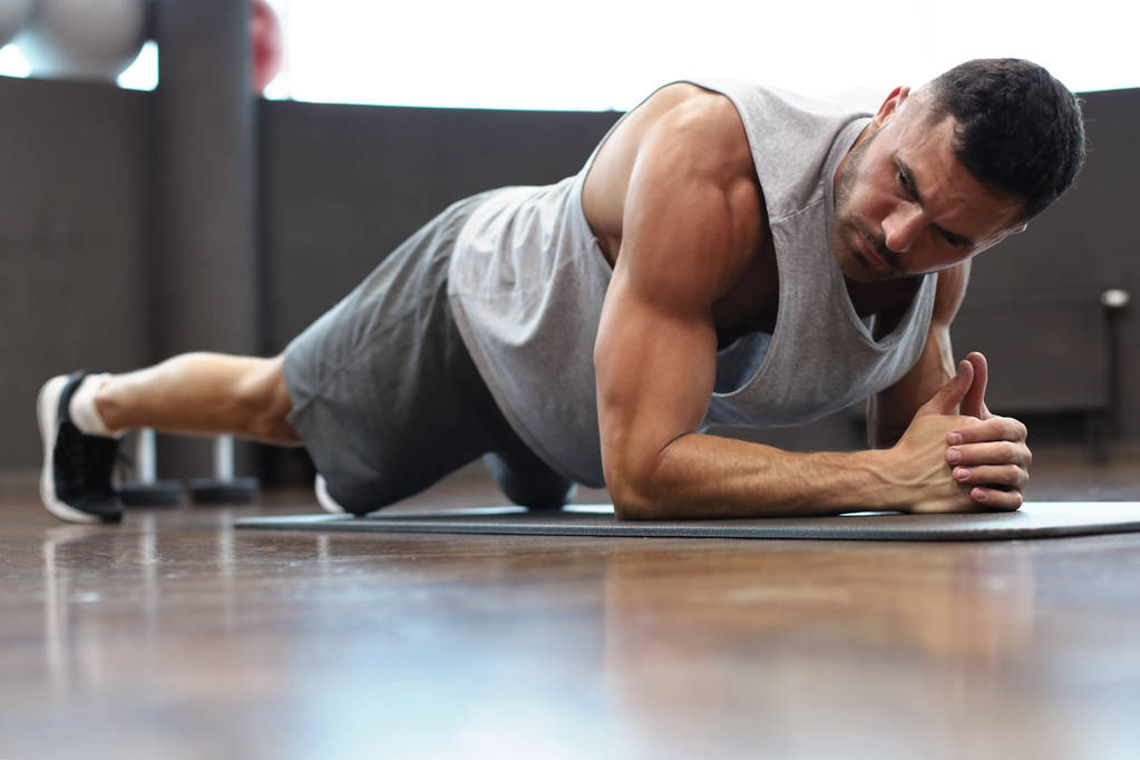 Porträt eines Fitnessmannes beim Planken im Fitnessstudio. - Foto, Bild