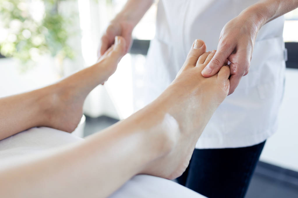 Вагітна жінка насолоджується рефлексологічним масажем ніг у оздоровчому спа-центрі
. - Фото, зображення