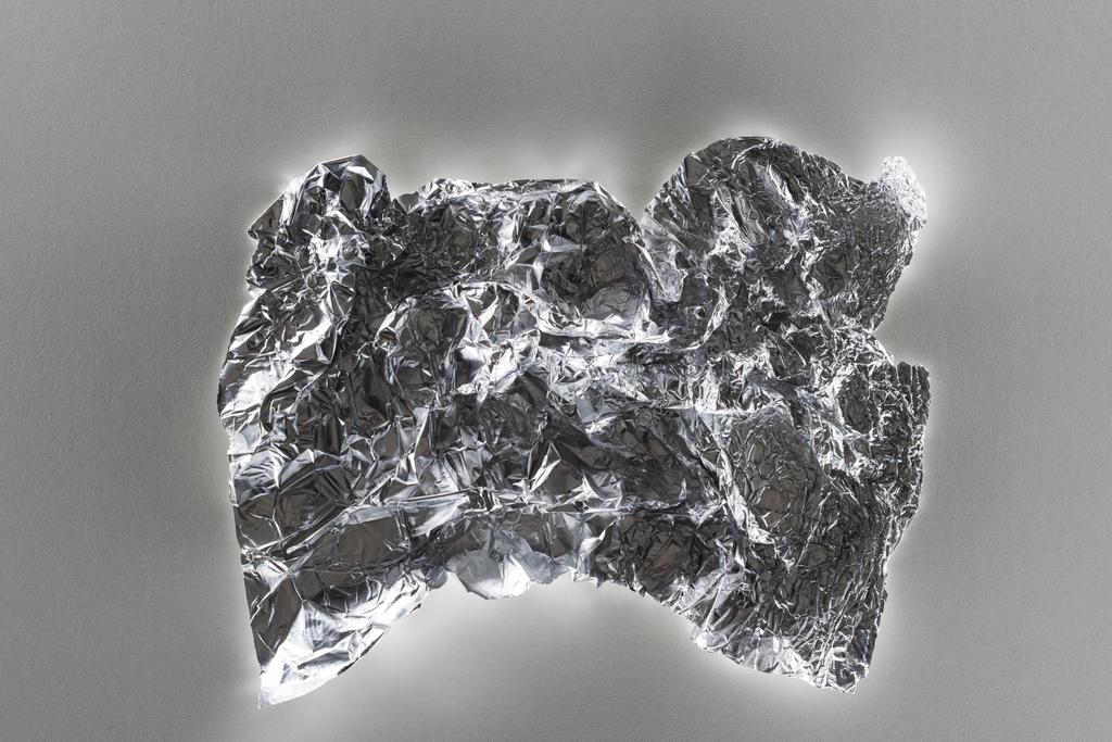 Κορυφαία όψη του γυαλιστερού τσαλακωμένο ασημένιο φύλλο σε γκρίζο φόντο - Φωτογραφία, εικόνα
