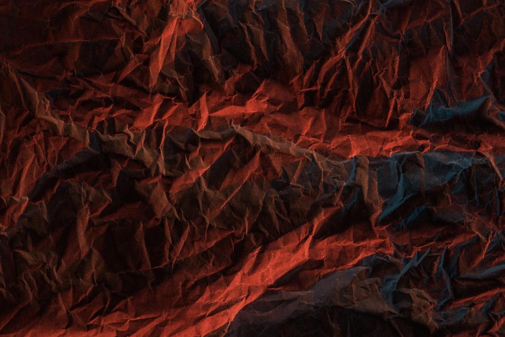 top view of crumpled paper with red colorful lighting in darkness - Photo, Image