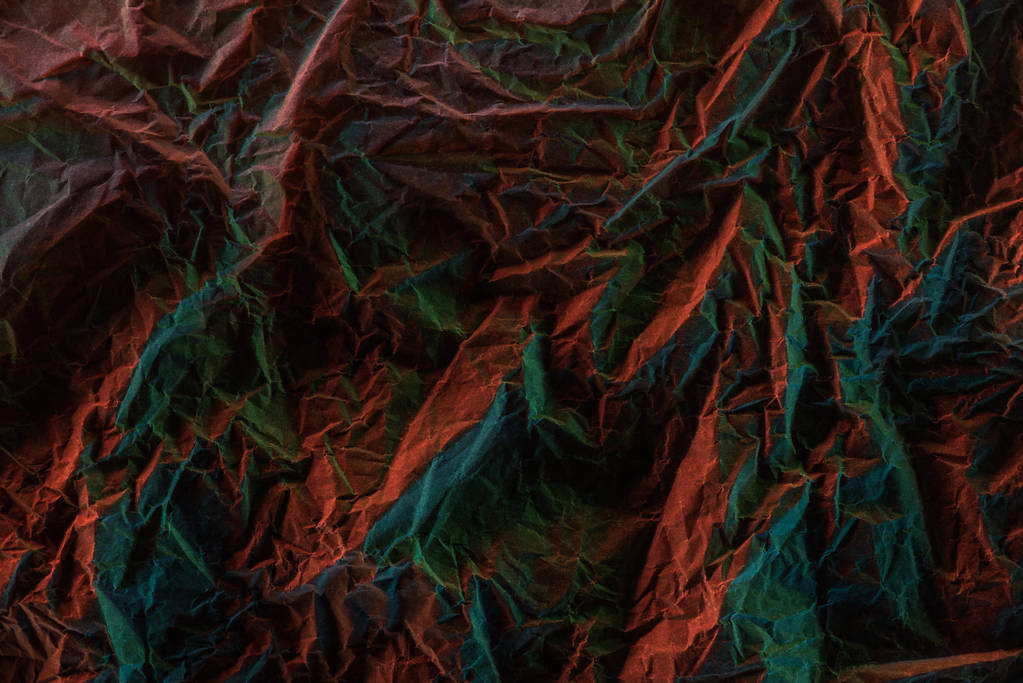 Κορυφαία όψη του τσαλακωμένο χαρτί με πολύχρωμο φωτισμό στο σκοτάδι - Φωτογραφία, εικόνα
