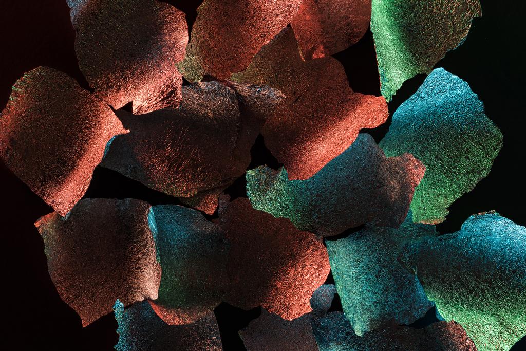abstract background of textured torn silver foil with colorful illumination isolated on black - Photo, Image