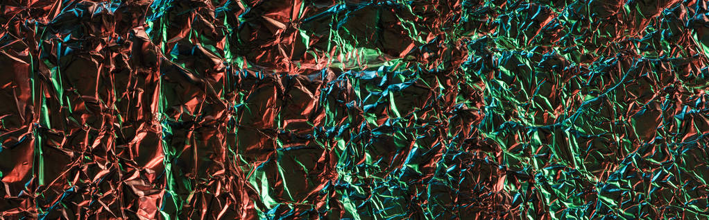 panoramische foto van glanzend verfrommeld folie met kleurrijke verlichting - Foto, afbeelding
