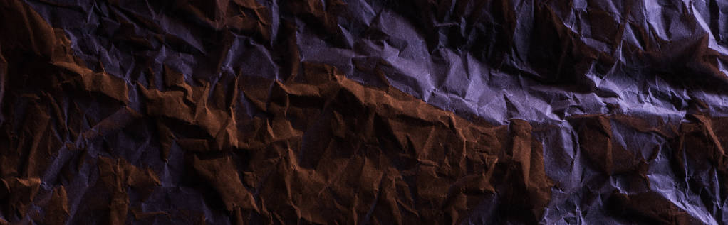 панорамный снимок скомканной бумаги с фиолетовым красочным освещением в темноте
 - Фото, изображение