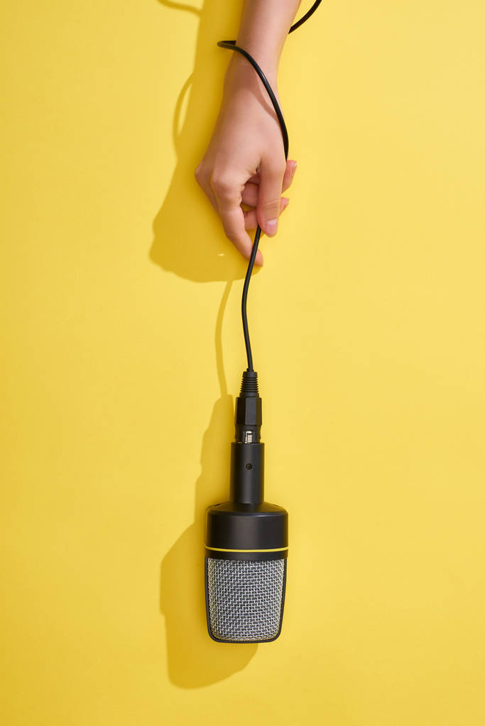 vista recortada de la mujer sosteniendo micrófono sobre fondo amarillo
  - Foto, Imagen