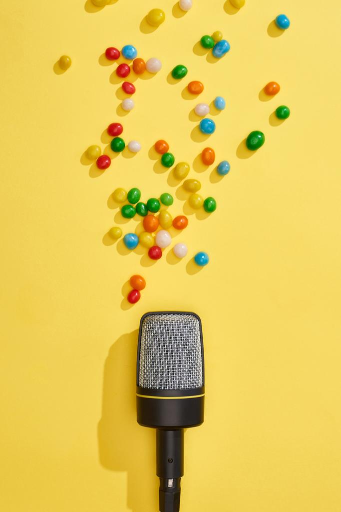 vue du haut du microphone avec des bonbons sur fond lumineux et coloré
  - Photo, image