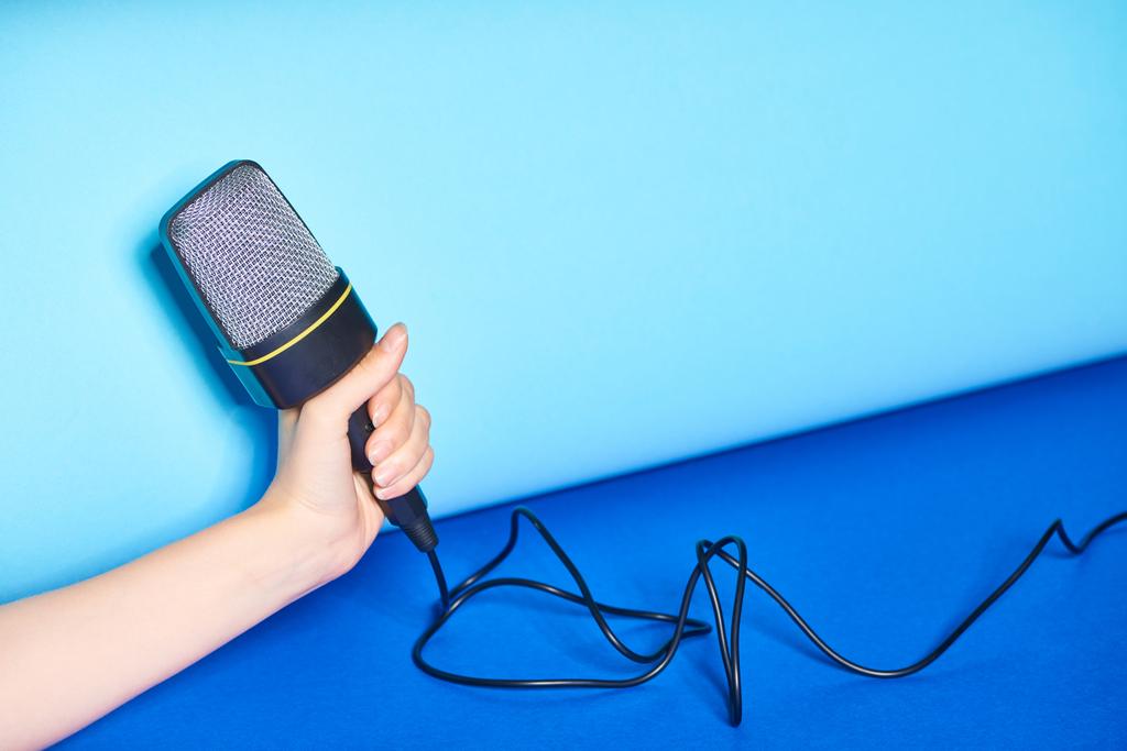 vista recortada de la mujer sosteniendo micrófono sobre fondo turquesa
  - Foto, Imagen
