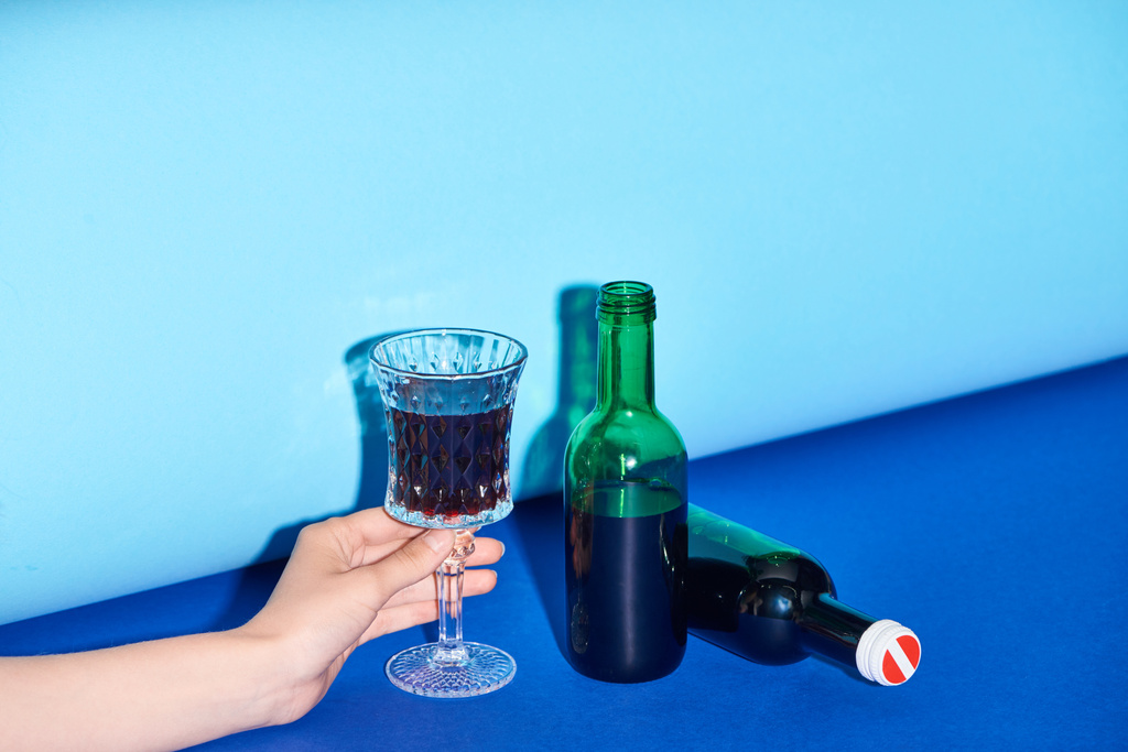 обрезанный вид женщины, держащей стакан с вином на красочном фоне
  - Фото, изображение