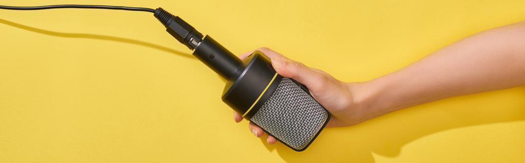 panoráma lövés nő kezében mikrofon sárga háttér  - Fotó, kép