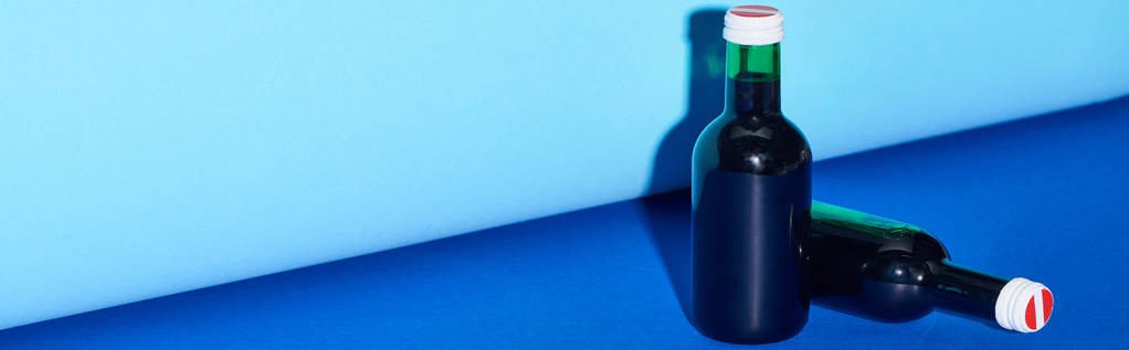 panoramiczny strzał butelek z winem na kolorowym tle  - Zdjęcie, obraz