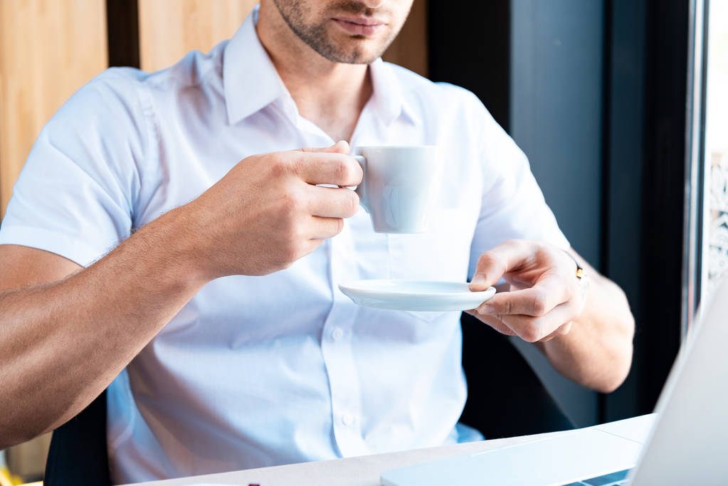 vue recadrée de l'homme tenant soucoupe et tasse de café dans le café
 - Photo, image