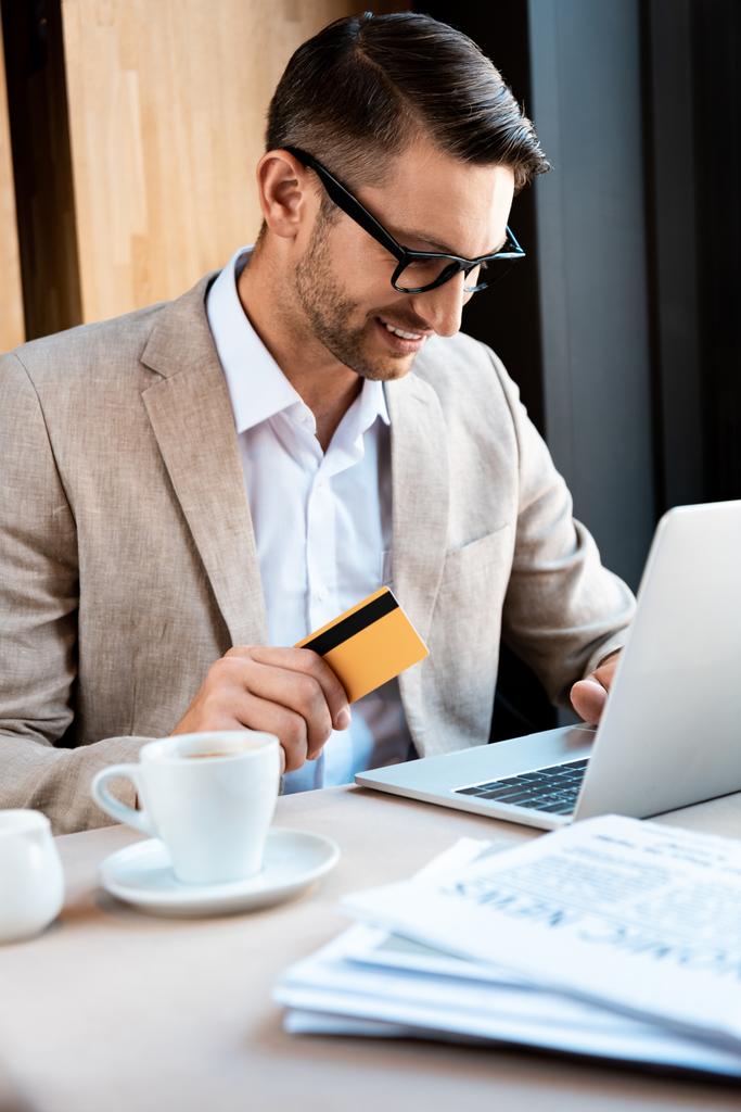 homme d'affaires souriant dans des lunettes avec carte de crédit et ordinateur portable dans le café
 - Photo, image