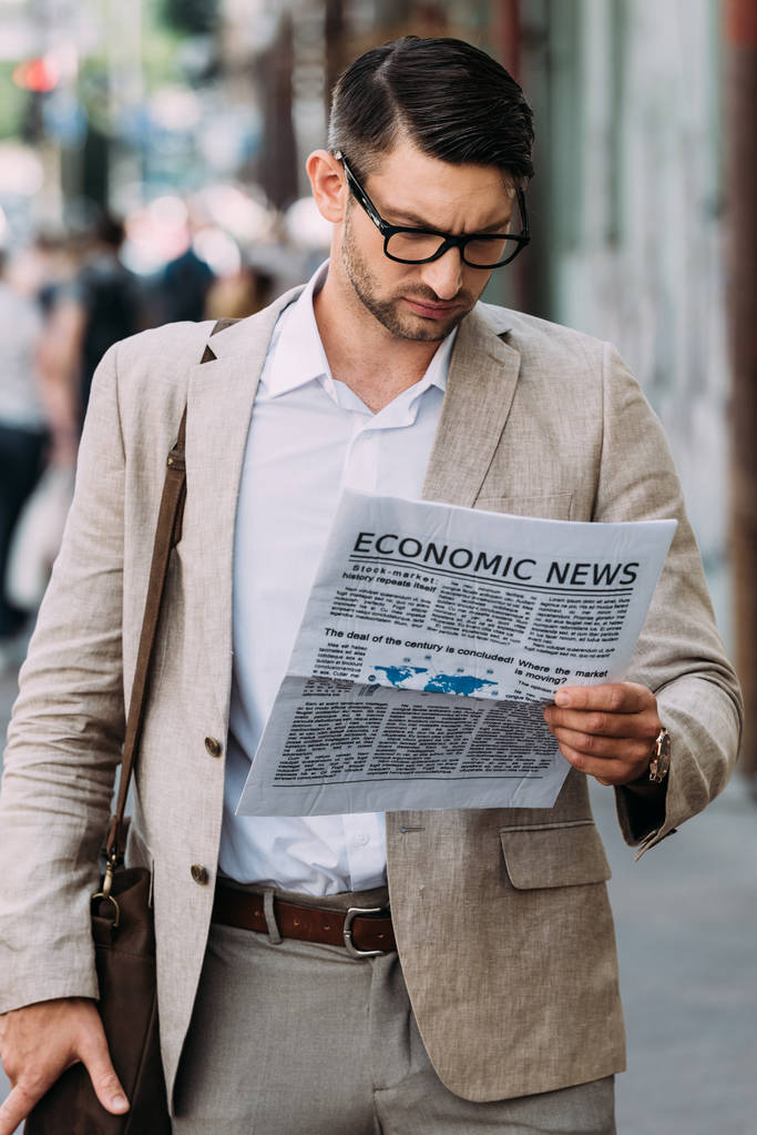 συγκεντρωμένος επιχειρηματίας σε γυαλιά διαβάζοντας εφημερίδα στο δρόμο - Φωτογραφία, εικόνα