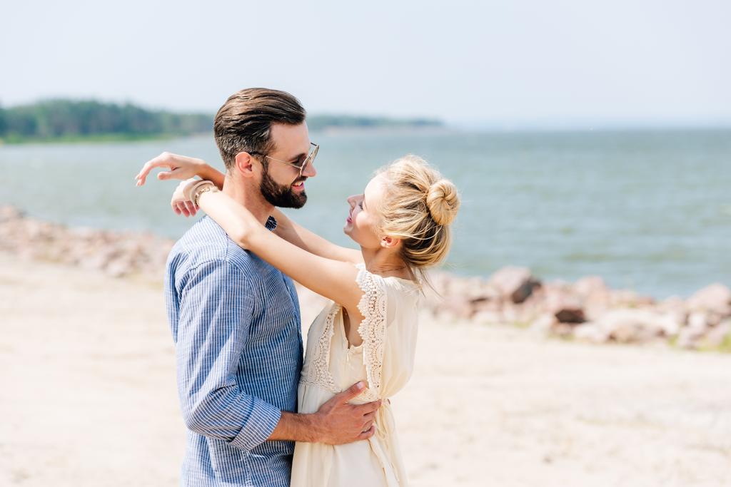 feliz mulher loira abraçando sorrindo namorado barbudo na praia
 - Foto, Imagem
