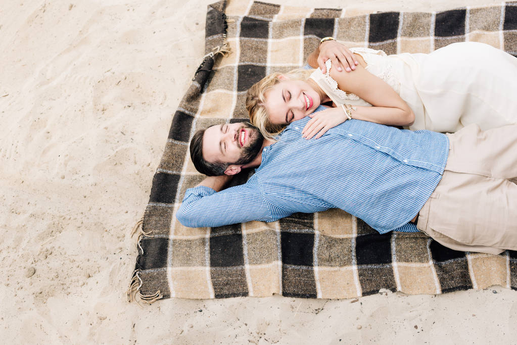 boldog pár feküdt együtt kockás takaró a homokos strandon - Fotó, kép