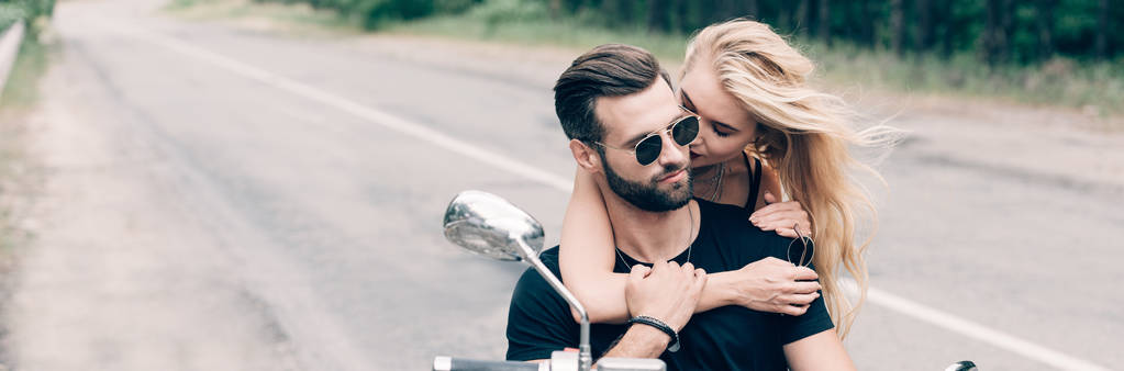 黒いオートバイに密接に抱き合うバイカーの若いカップル、パノラマショット - 写真・画像