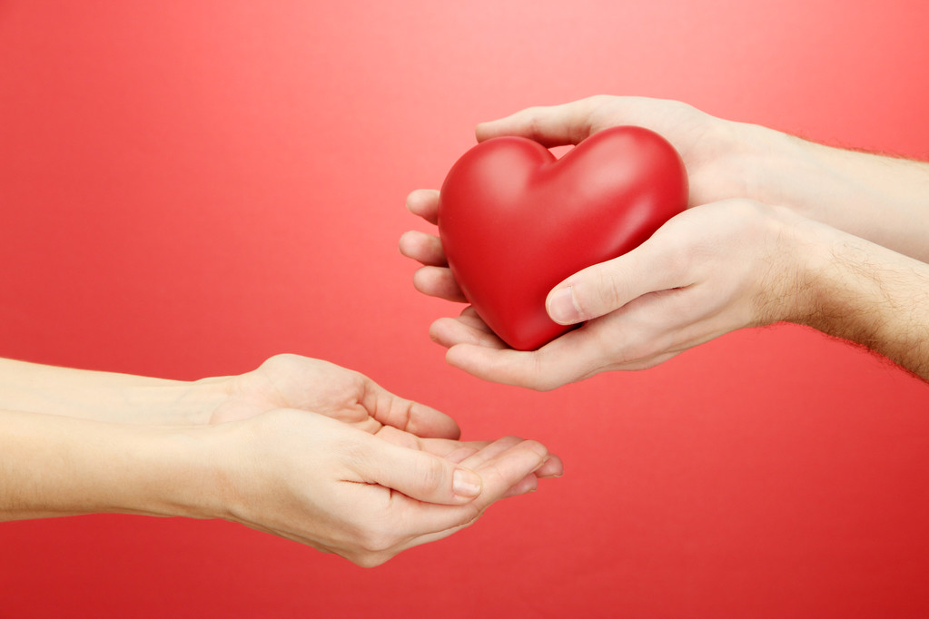 Červené srdce v rukou žena a muž, na červeném pozadí - Fotografie, Obrázek