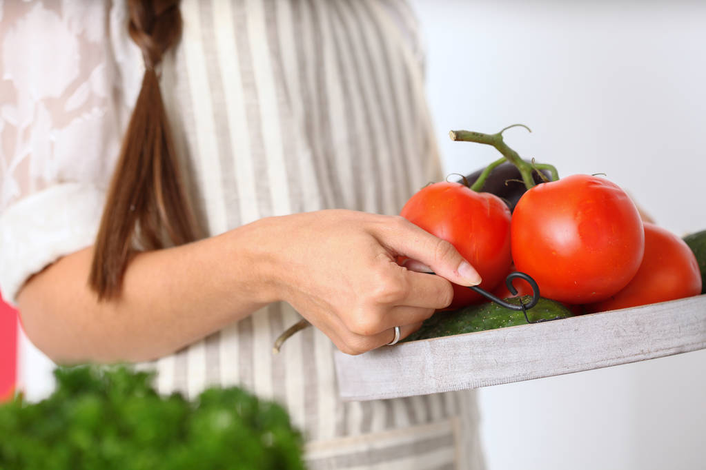 Усміхнена молода жінка тримає овочі, що стоять на кухні. усміхнена молода жінка
 - Фото, зображення