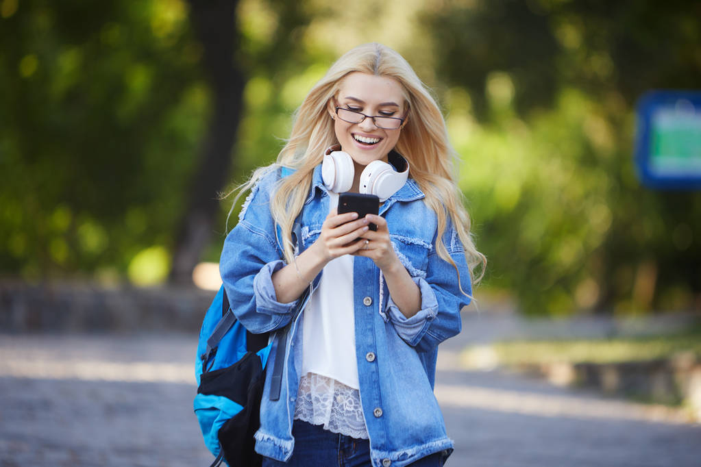 Frontansicht junger aufgeregter Studentinnen, die online per Mobiltelefon auf einem Universitätscampus oder einer Straße gute Nachrichten erhalten. Konzept des Siegers - Foto, Bild
