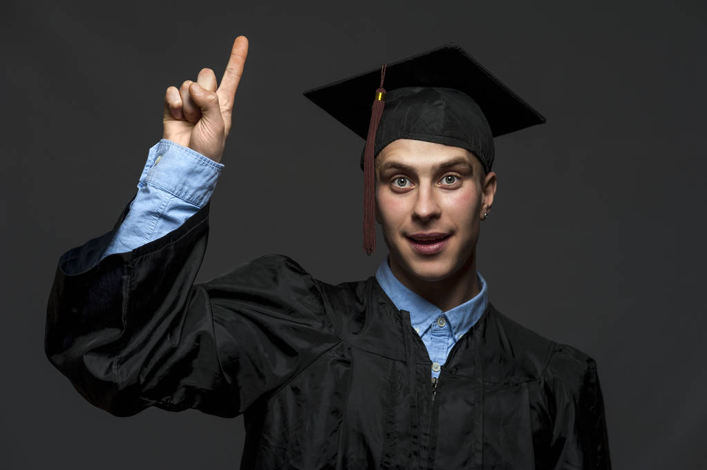 Πορτρέτο του απόφοιτου ενήλικα αρσενικό μαθητή σε μαύρο φόρεμα αποφοίτησης με καπέλο - Φωτογραφία, εικόνα