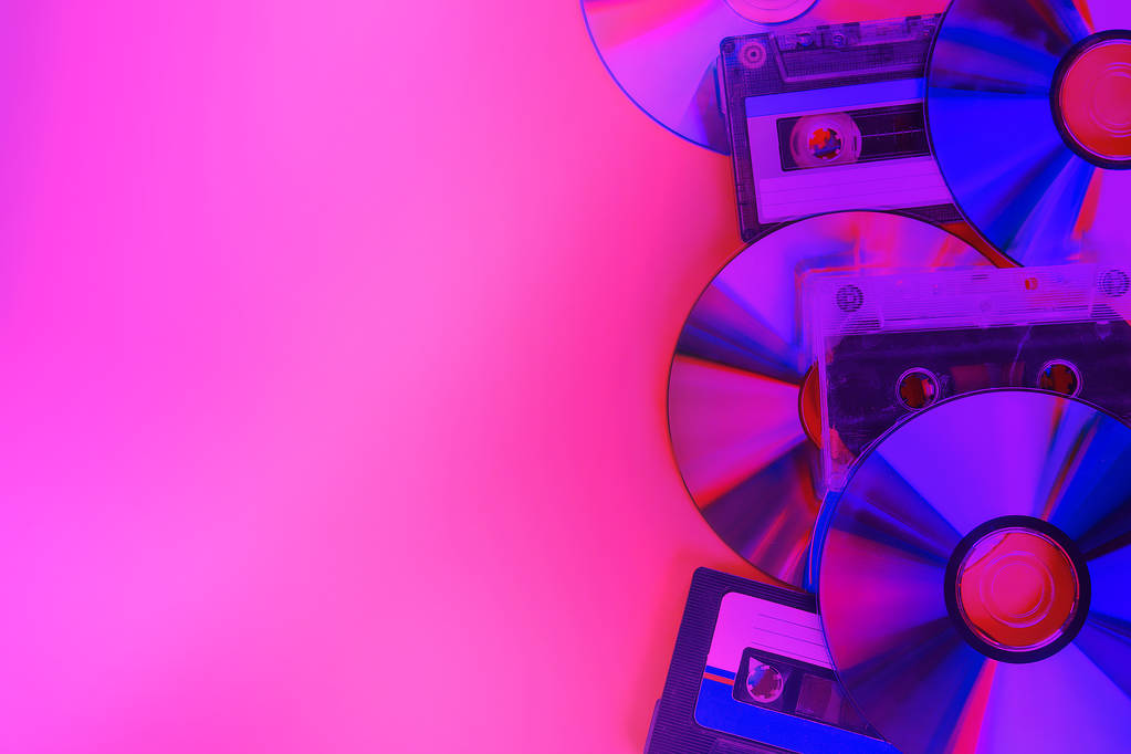 Discos de CD y casetes de audio sobre fondo de neón rosa. Minimalismo
. - Foto, imagen