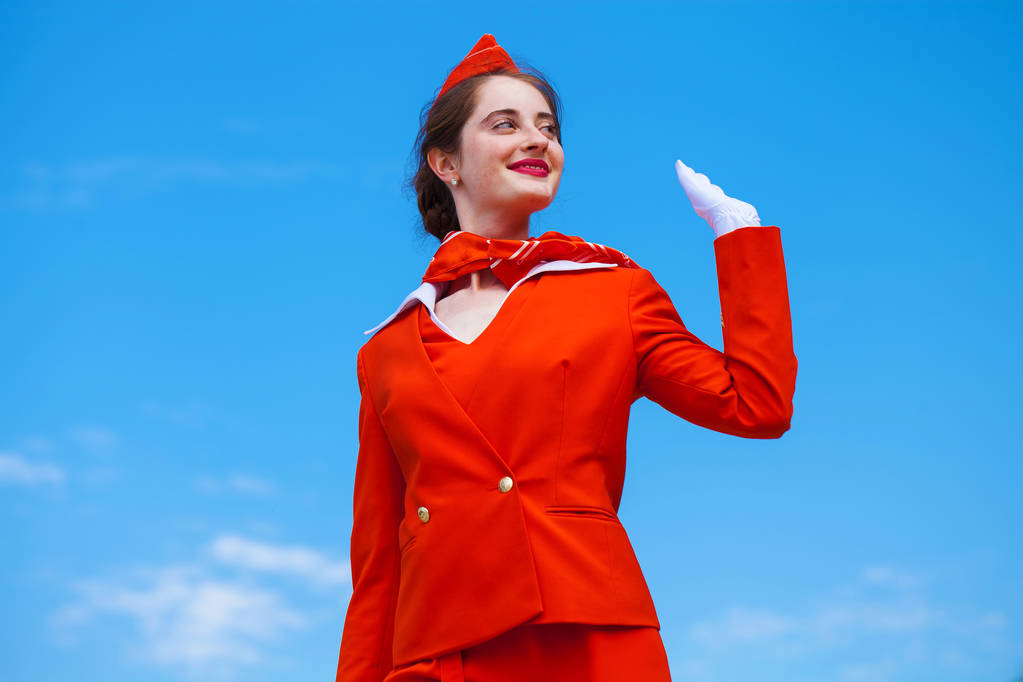 Joven azafata vestida con uniforme oficial rojo de Airlines
  - Foto, Imagen