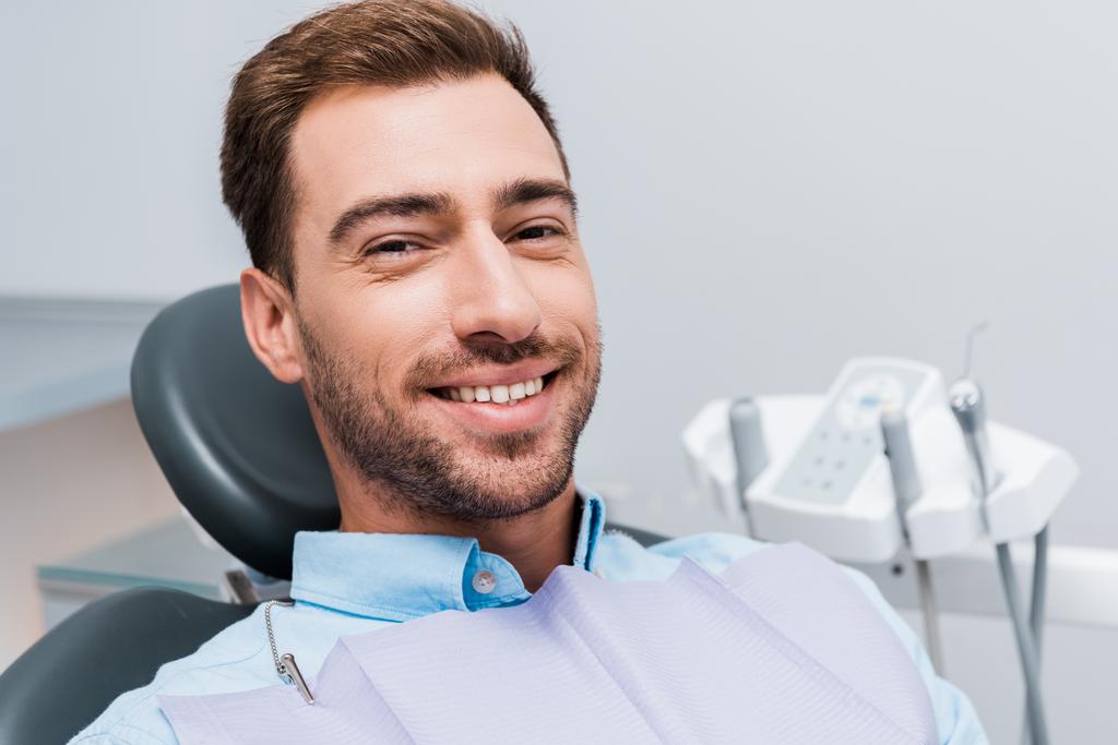 hombre barbudo alegre sonriendo y mirando a la cámara en la clínica dental
  - Foto, Imagen