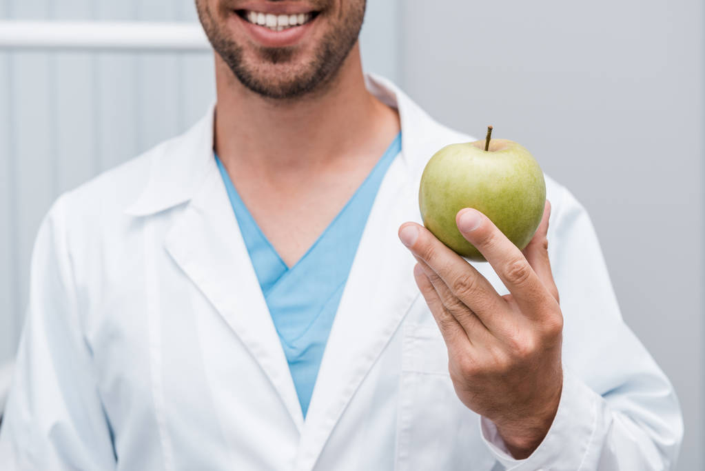 abgeschnittene Ansicht eines glücklichen bärtigen Mannes mit grünem und schmackhaftem Apfel  - Foto, Bild