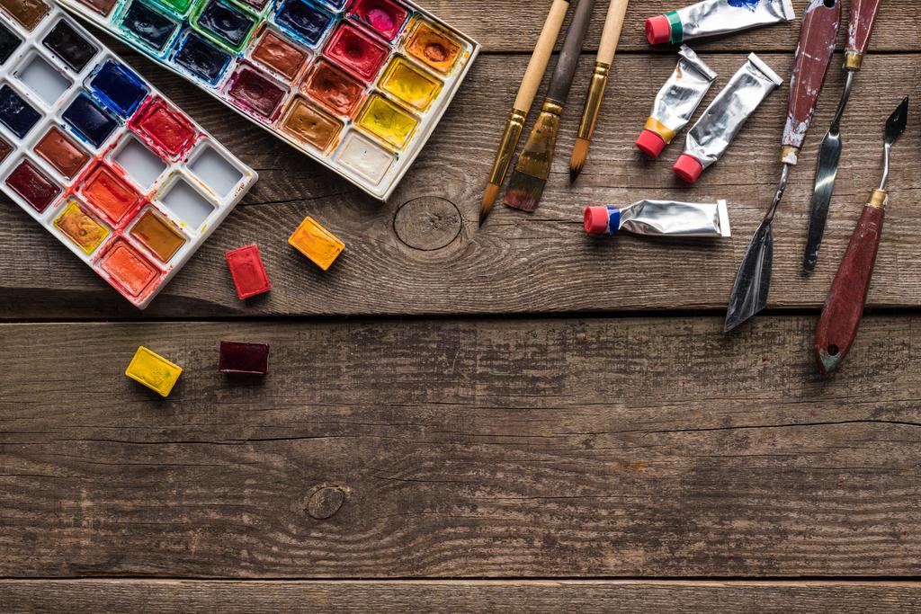 Draufsicht auf bunte Farbpaletten und Zeichenwerkzeuge auf Holzoberfläche mit Kopierraum - Foto, Bild
