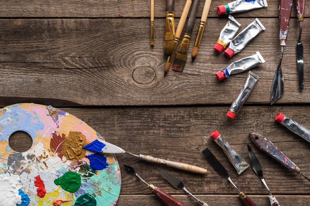 top view of colorful palette with paints and drawing tools on wooden surface with copy space - Photo, Image