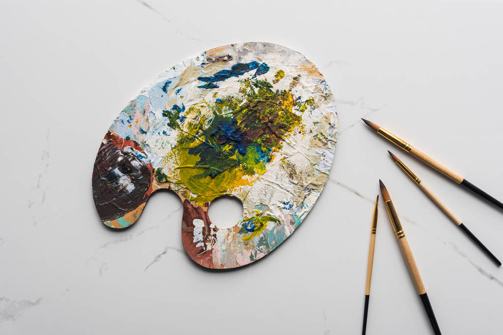 vista dall'alto di tavolozza colorata con vernici a olio vicino pennelli su marmo superficie bianca
 - Foto, immagini