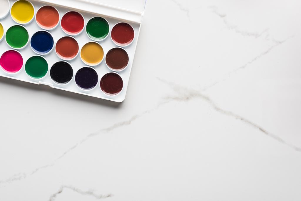 vista superior de la paleta de pintura de acuarela en la superficie blanca de mármol con espacio de copia
 - Foto, Imagen