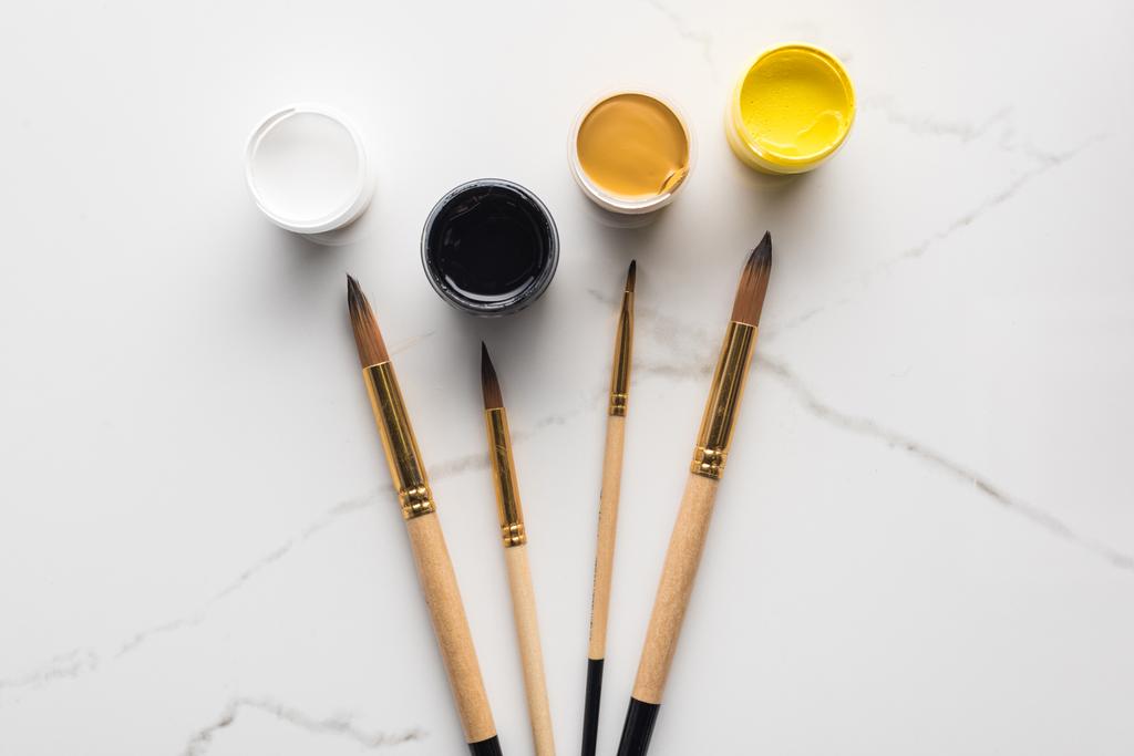 mermer beyaz yüzey üzerinde guaj boyaları ve boya fırçalarının üst görünümü - Fotoğraf, Görsel