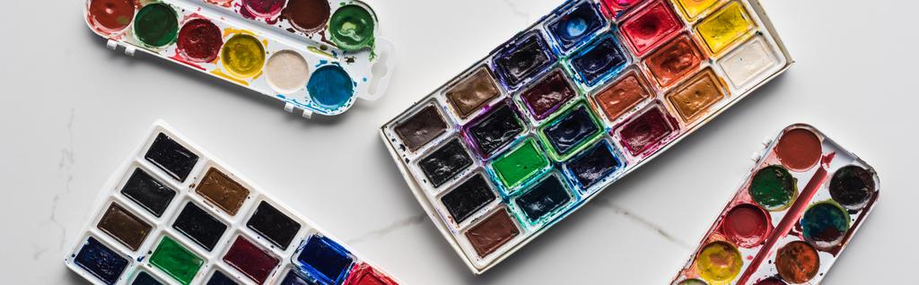 vista superior de coloridas paletas de pintura sobre la superficie blanca de mármol, plano panorámico
 - Foto, Imagen