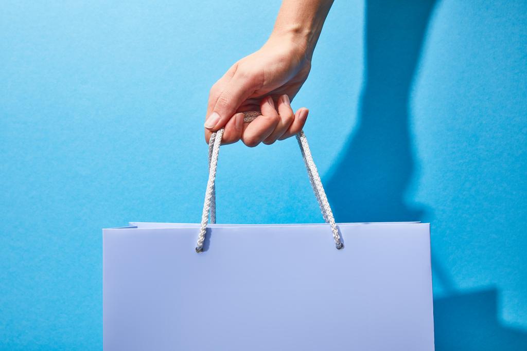 обрізаний вид жінки, що тримає фіолетовий сумку для покупок на синьому
  - Фото, зображення