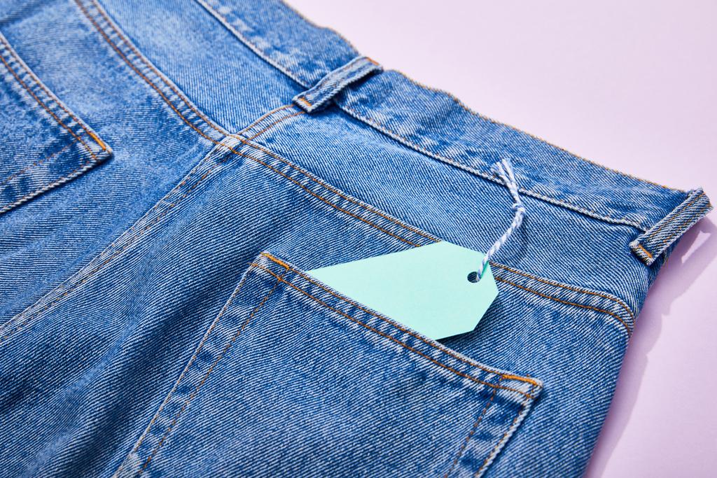 vista de perto de etiqueta de venda de papel turquesa na corda em jeans em violeta
  - Foto, Imagem
