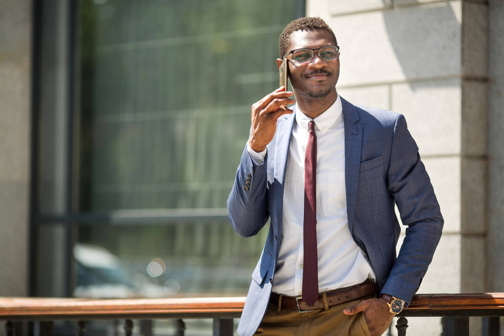 guapo joven adulto africano hombre en traje y gafas hablando por teléfono
 - Foto, imagen