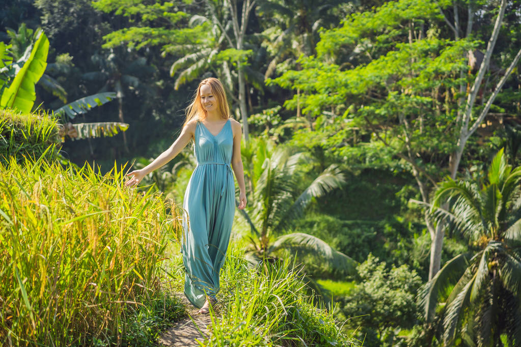 Beautiful young woman walk at typical Asian hillside with rice farming, mountain shape green cascade rice field terraces paddies. Ubud, Bali, Indonesia. Bali travel concept - Photo, Image