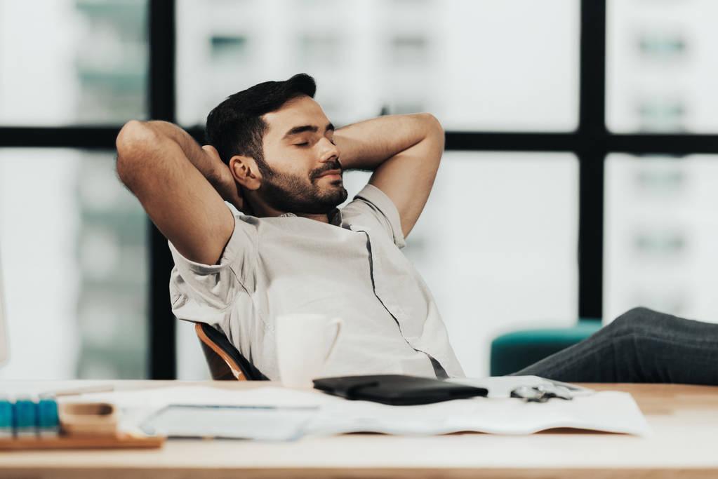 リラックスして成功したビジネスマンは、現代のオフィスで座って一生懸命働いた後、リラックスして休みます。時間の健康的なケア。事業コンセプト  - 写真・画像