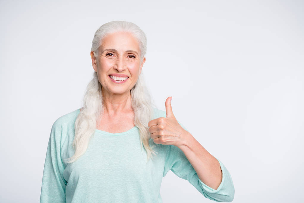 Portréja szép nyugdíjas mutató hüvelykujj fel ajánlja promo viselő türkiz pulóver izolált fehér háttér - Fotó, kép