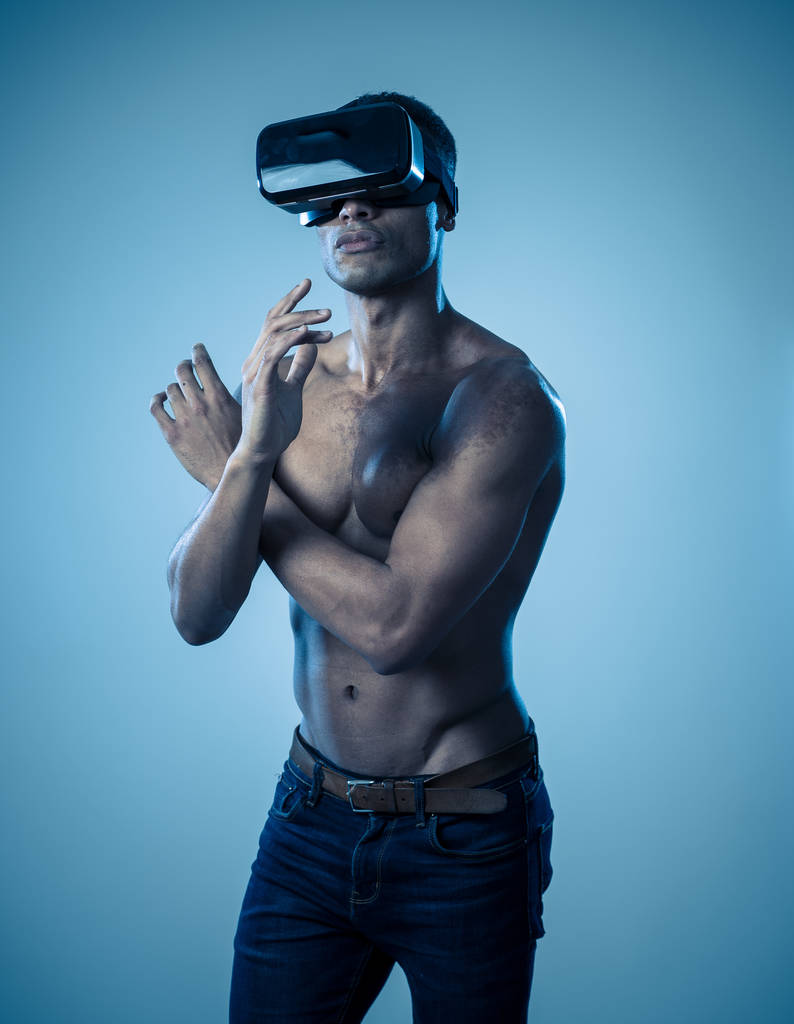 Homme afro-américain attrayant utilisant des lunettes VR augmentées explorant le monde 3D se sentant excité par la simulation, de nouvelles sensations et désirs. En réalité virtuelle, innovation et concept de nouvelle technologie
. - Photo, image