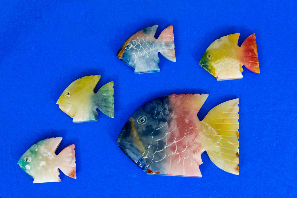 ψάρια κατασκευασμένα από πέτρα σε χρωματιστό φόντο  - Φωτογραφία, εικόνα