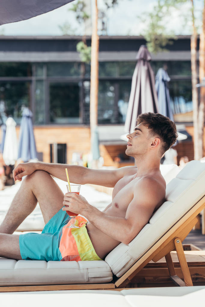 unenomainen nuori mies katselee pois rentoutuessaan lepotilassa lasillisella virkistävää juomaa
 - Valokuva, kuva