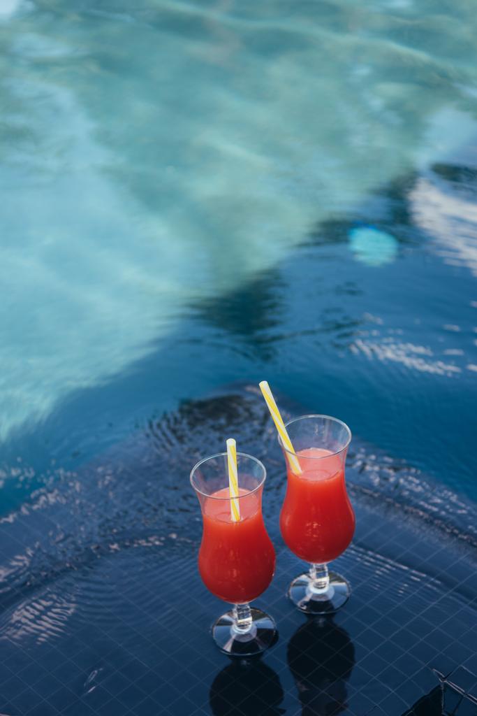 two glasses with natural fruit refreshing beverage at poolside - Photo, Image