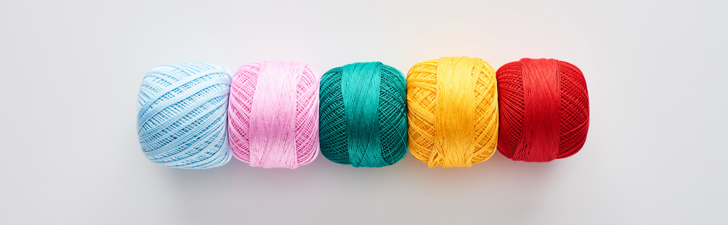 plan panoramique de boules de fils à tricoter lumineuses et colorées sur fond blanc
  - Photo, image
