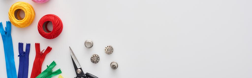 tiro panorâmico de zíperes, tesoura, dedais, bolas de fio de tricô, bobinas no fundo branco
  - Foto, Imagem